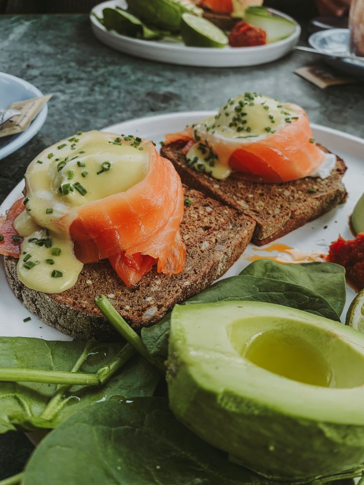 dos tostadas con salmon y queso por encima y un aguacate